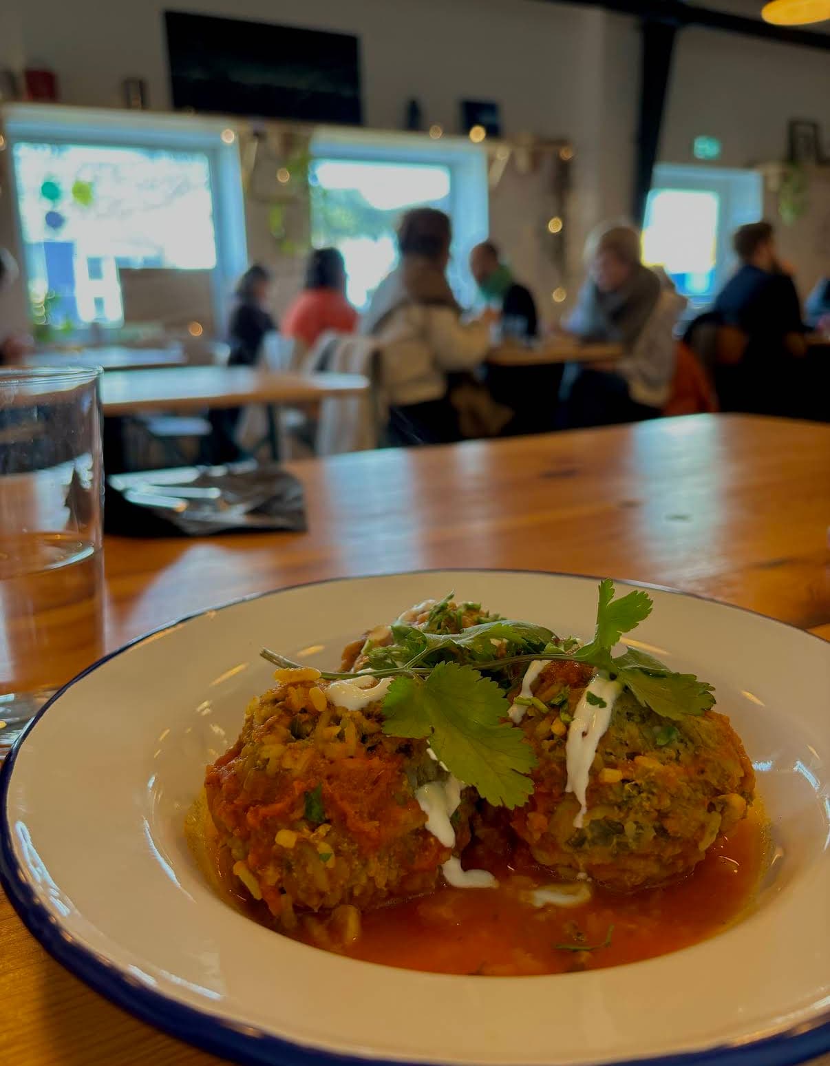 Salle du restaurant Polaris — longues tables en bois, lumière haute, et au premier plan un plat de frikadeller